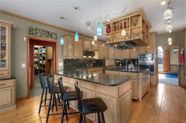 104 Aspen Dr NE, Calhoun, GA 30701 - kitchen featuring an island with sink, light wood-style floors, decorative backsplash, crown molding, and dark stone countertops