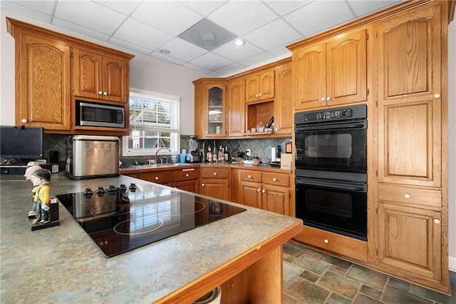 104 Aspen Dr NE, Calhoun, GA 30701 - kitchen featuring black appliances, a sink, a paneled ceiling, brown cabinetry, and glass insert cabinets