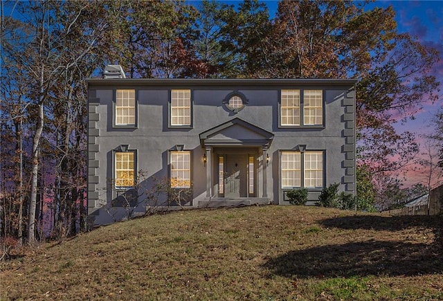 colonial house featuring a yard and stucco siding