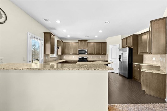 1566 Wilson Manor Cir, Lawrenceville, GA 30045 - kitchen featuring light stone counters, dark wood finished floors, stainless steel appliances, backsplash, and a peninsula