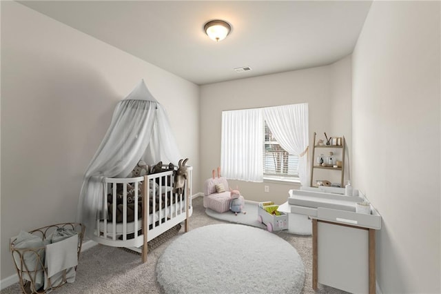 carpeted bedroom with visible vents, a crib, and baseboards