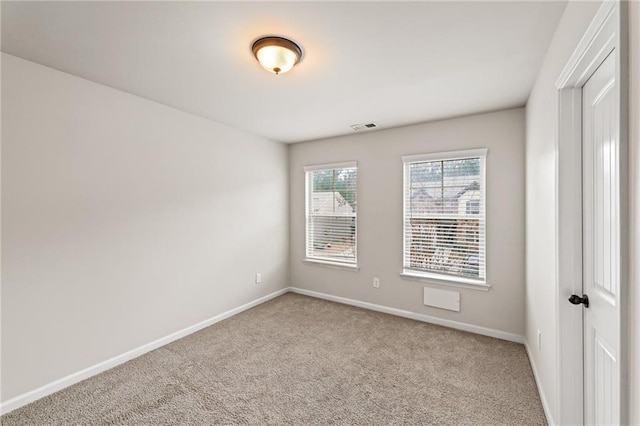 spare room featuring carpet floors, visible vents, and baseboards