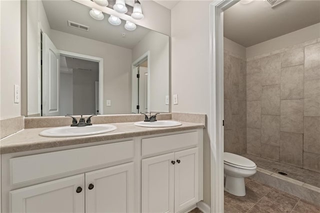 full bath featuring toilet, double vanity, visible vents, and a sink