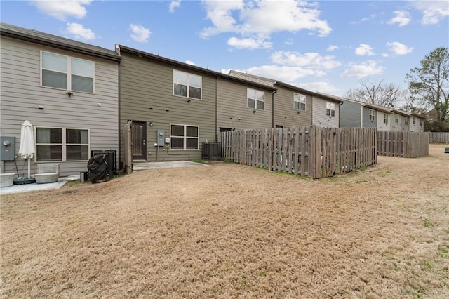 rear view of property featuring central AC unit, a patio area, fence, and a yard