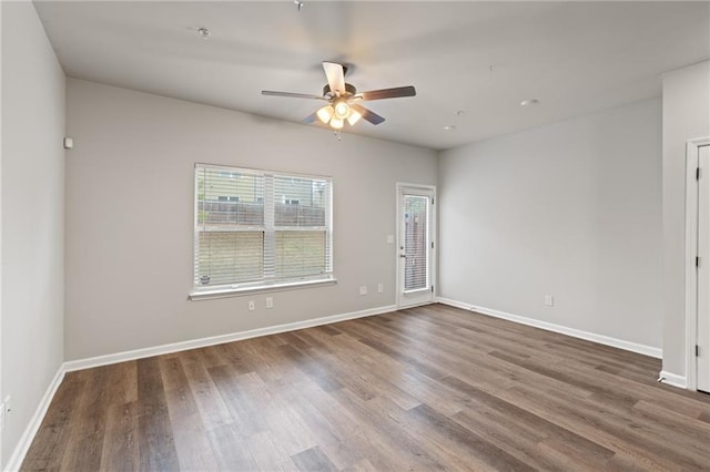 spare room with baseboards, a wealth of natural light, and wood finished floors