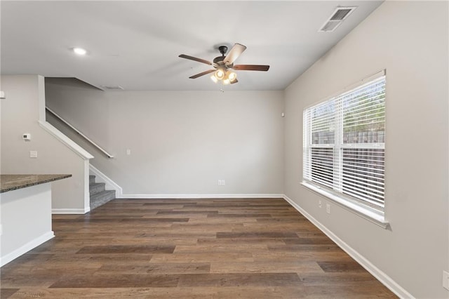 empty room with baseboards, visible vents, a ceiling fan, stairway, and wood finished floors