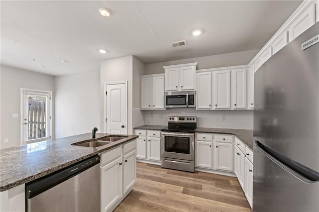 kitchen featuring stainless steel appliances, visible vents, light wood-style flooring, white cabinetry, and a sink