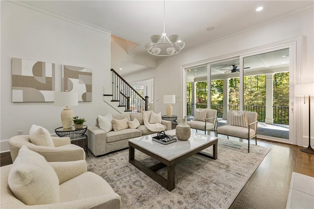 living room with crown molding, ceiling fan with notable chandelier, and hardwood / wood-style floors