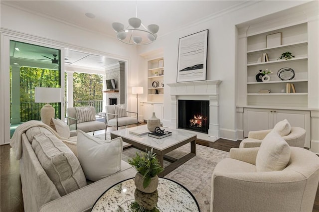 living room with ornamental molding, a chandelier, dark hardwood / wood-style floors, and built in shelves