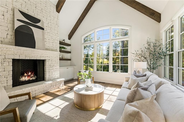 living room featuring beam ceiling, high vaulted ceiling, a fireplace, and light wood-type flooring