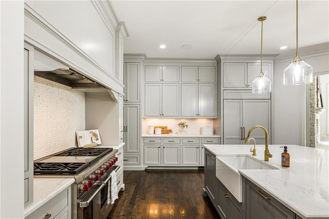 kitchen featuring dark hardwood / wood-style flooring, sink, pendant lighting, light stone counters, and premium appliances