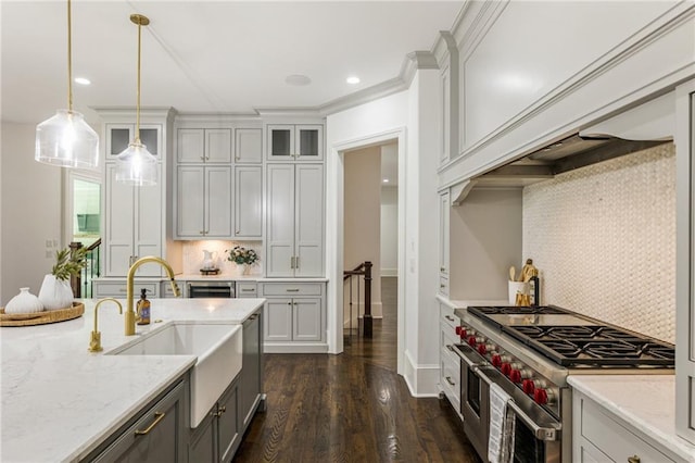 kitchen featuring sink, range with two ovens, pendant lighting, dark wood-type flooring, and light stone counters