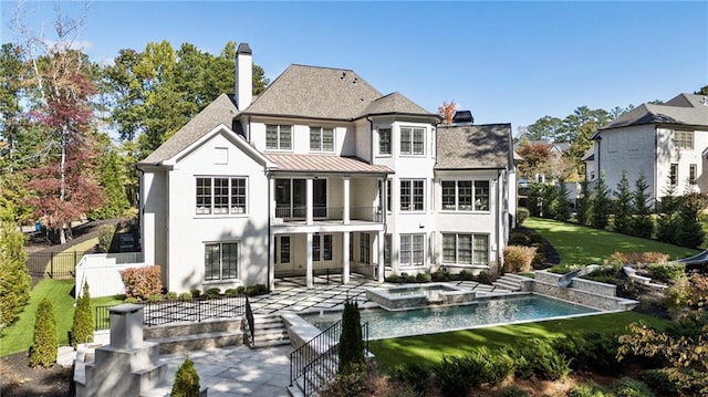 back of house featuring a patio, a swimming pool with hot tub, and a lawn