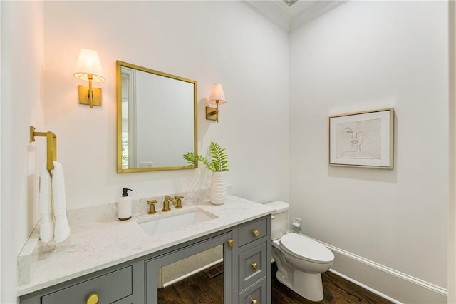 bathroom featuring vanity, ornamental molding, hardwood / wood-style flooring, and toilet