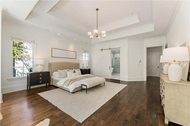 bedroom featuring dark hardwood / wood-style flooring, a barn door, a tray ceiling, crown molding, and ensuite bath