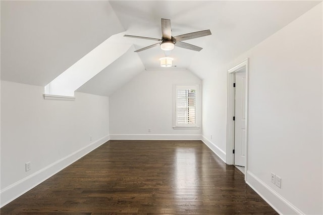 additional living space with vaulted ceiling with skylight, ceiling fan, and dark hardwood / wood-style flooring