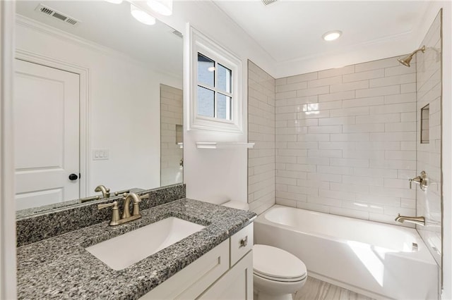 full bathroom featuring tiled shower / bath, vanity, crown molding, and toilet