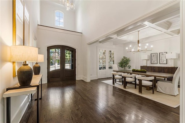 foyer entrance featuring french doors, coffered ceiling, dark wood-type flooring, beam ceiling, and a chandelier