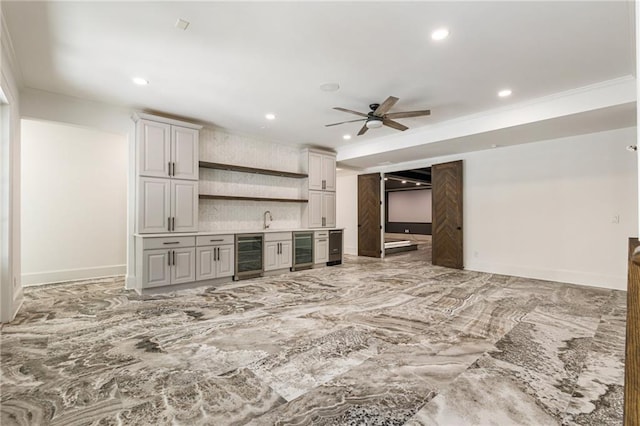 unfurnished living room with ceiling fan, ornamental molding, indoor bar, and beverage cooler