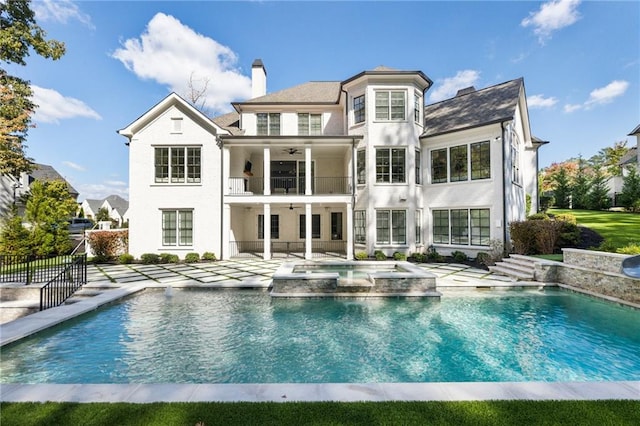 rear view of property with a patio area, a balcony, and a swimming pool with hot tub