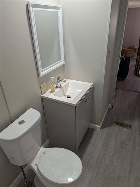 bathroom with toilet, wood-type flooring, and vanity