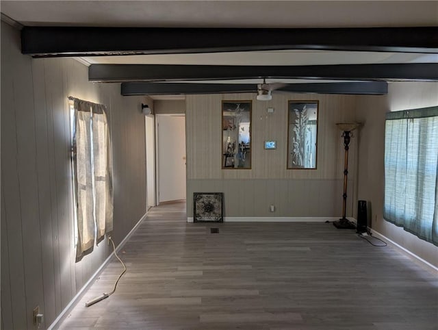 unfurnished living room featuring plenty of natural light, beamed ceiling, and wood-type flooring