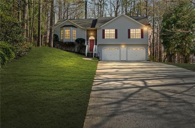 raised ranch featuring entry steps, an attached garage, concrete driveway, and a front lawn