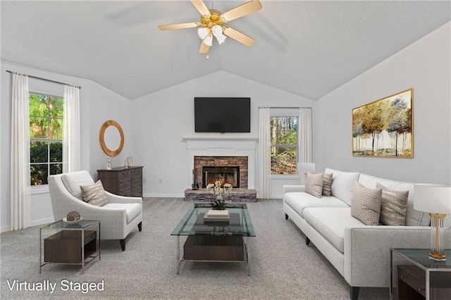 carpeted living room with a healthy amount of sunlight, ceiling fan, a fireplace, and vaulted ceiling