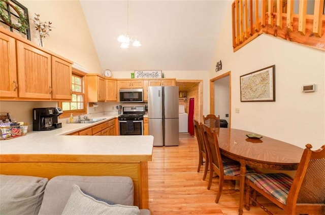 kitchen featuring a sink, stainless steel appliances, light wood-style floors, an inviting chandelier, and light countertops