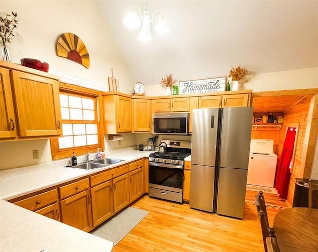 kitchen with a sink, appliances with stainless steel finishes, light wood finished floors, washer / dryer, and light countertops