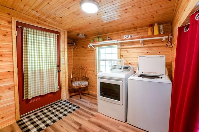 laundry room featuring light wood-style floors, wood walls, wooden ceiling, laundry area, and washing machine and clothes dryer