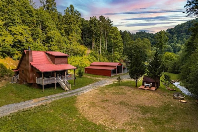 aerial view at dusk featuring a forest view