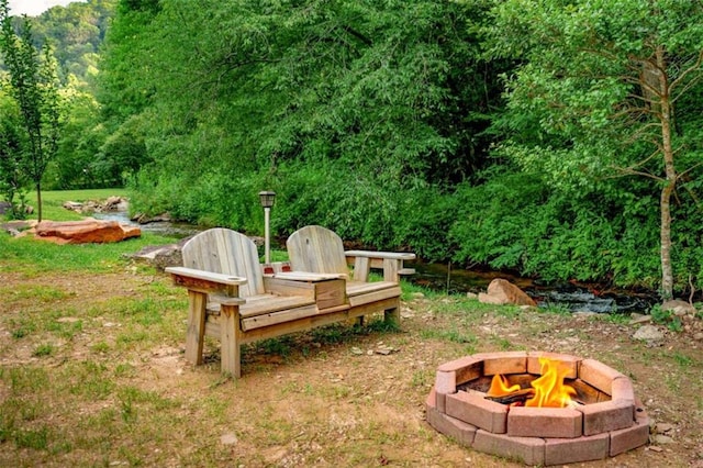 view of yard with a fire pit and a wooded view