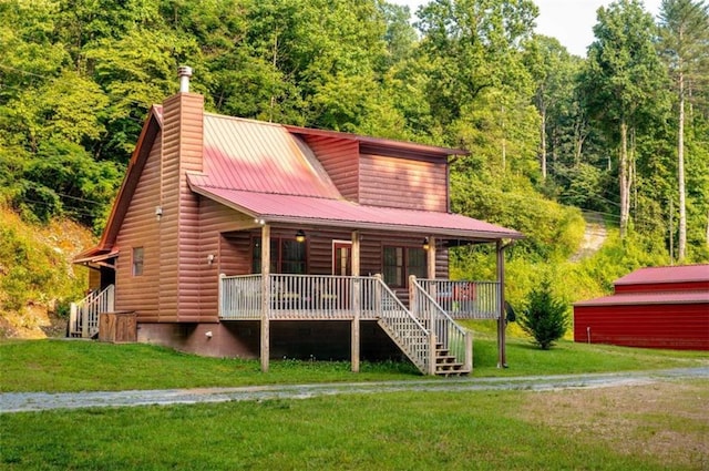 view of front of home with a front lawn, a view of trees, a porch, metal roof, and a chimney