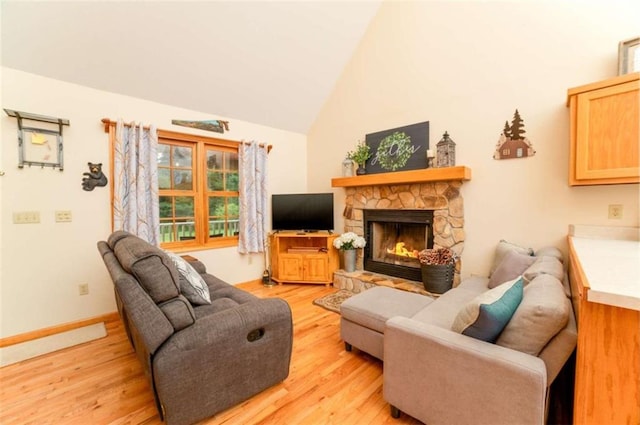 living room with baseboards, lofted ceiling, light wood-style floors, and a fireplace