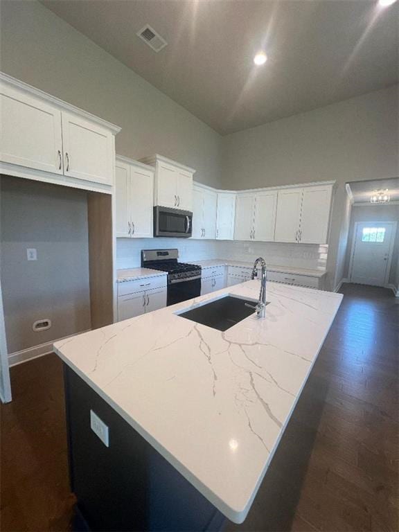 kitchen with appliances with stainless steel finishes, a kitchen island with sink, and white cabinets