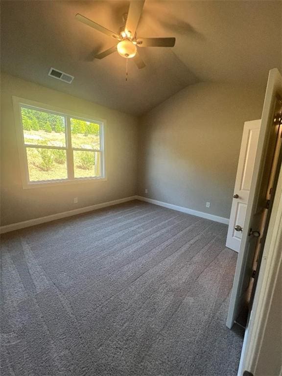 spare room with dark colored carpet, vaulted ceiling, and ceiling fan