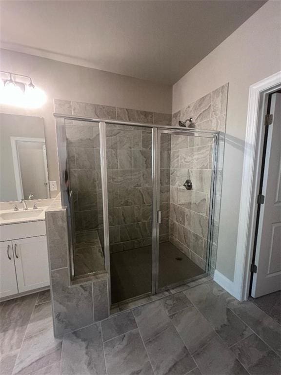 bathroom featuring a shower with door and vanity