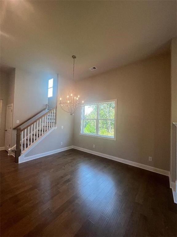 unfurnished room featuring dark hardwood / wood-style floors, a chandelier, and a healthy amount of sunlight