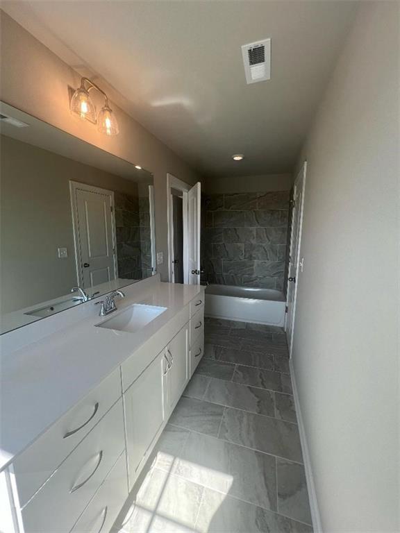 bathroom featuring vanity, tiled shower / bath combo, and tile patterned flooring