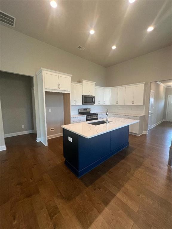 kitchen with a kitchen island with sink, stainless steel appliances, dark hardwood / wood-style flooring, and white cabinetry