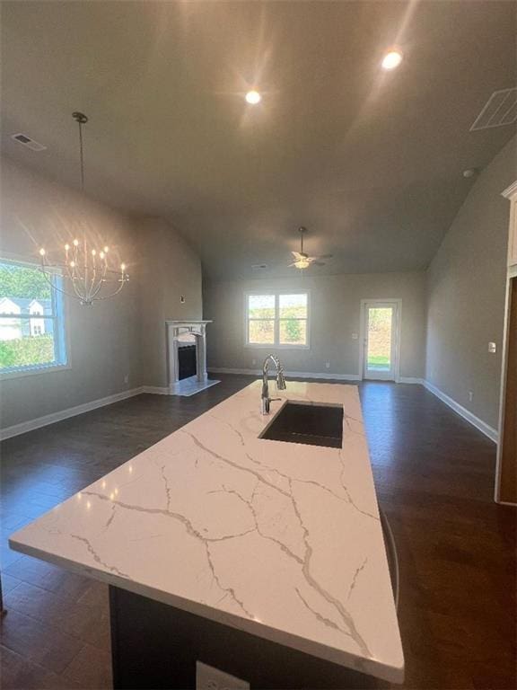 kitchen with an island with sink, dark wood-type flooring, decorative light fixtures, and ceiling fan with notable chandelier