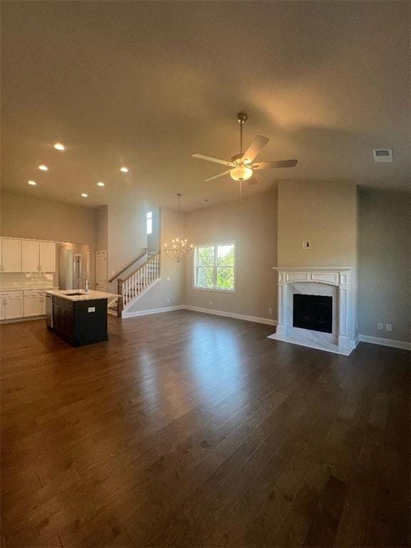 unfurnished living room with ceiling fan with notable chandelier, dark hardwood / wood-style floors, and sink