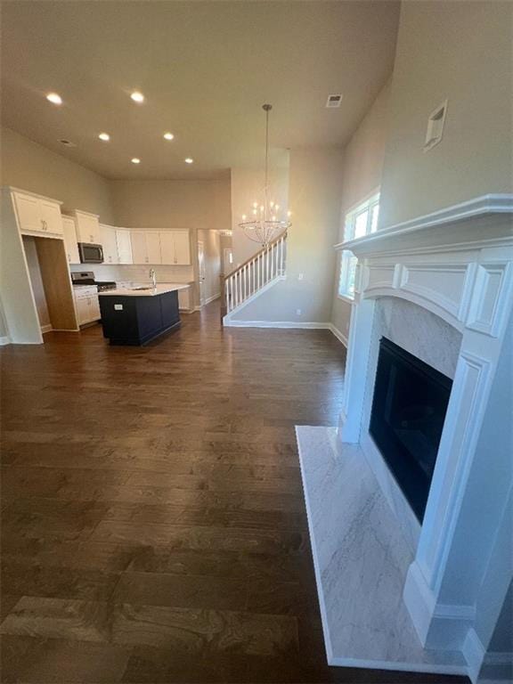 unfurnished living room featuring a premium fireplace, an inviting chandelier, and dark hardwood / wood-style flooring