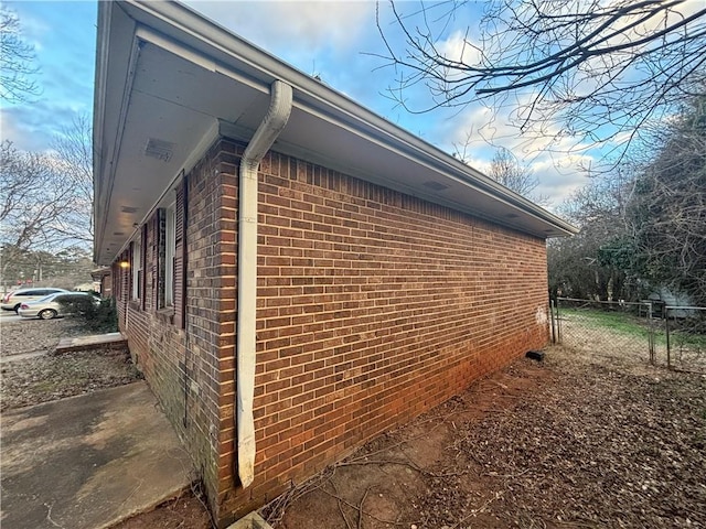 view of property exterior with fence and brick siding