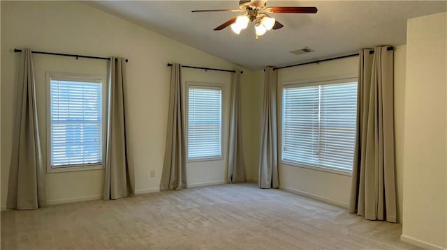 carpeted spare room featuring lofted ceiling, baseboards, visible vents, and a ceiling fan