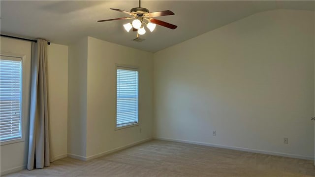 spare room with lofted ceiling, ceiling fan, light carpet, visible vents, and baseboards