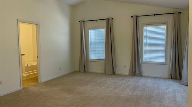 carpeted empty room featuring vaulted ceiling and baseboards