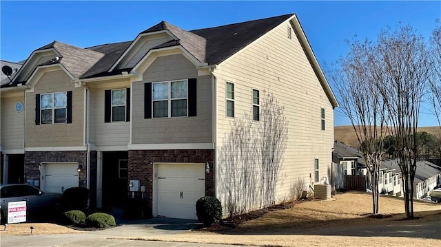 view of front of home with an attached garage, driveway, cooling unit, and brick siding