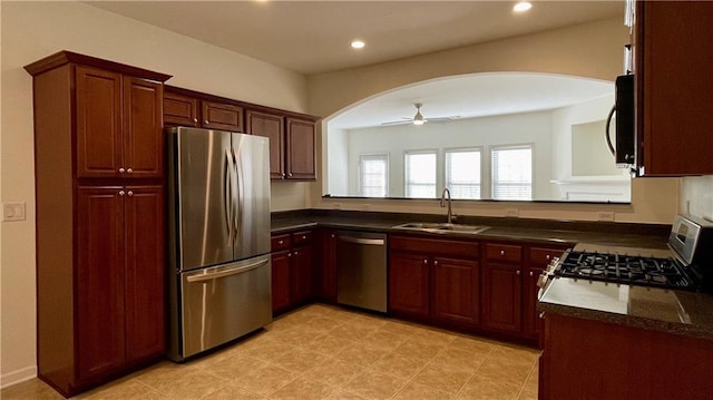 kitchen with ceiling fan, stainless steel appliances, dark countertops, and a sink